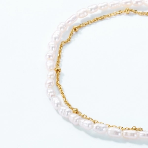 Macro detail of double-layer bracelet featuring white freshwater pearls and golden bead chain