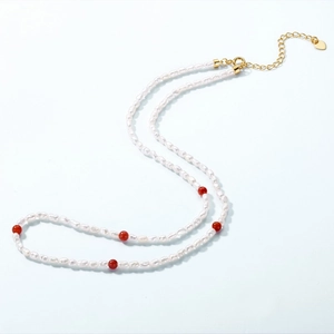 Collier élégant en perles avec perles d'agate rouge et breloque cœur dorée sur fond clair