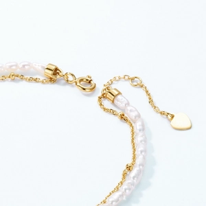 Close-up of double-layer freshwater pearl bracelet with golden heart pendant and clasp