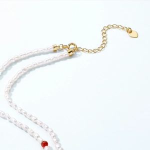 Détail du collier de perles baroques avec perle agate rouge et pendentif cœur doré