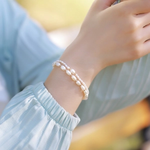 Detail of double-layered pearl bracelet with small gold beads on model wrist