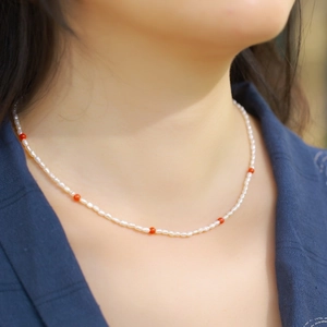 Élégant collier de perles avec perles d'agate rouge porté par mannequin sur chemise bleue