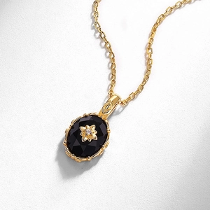 Détail du collier en argent doré avec agate noire ovale et relief de fleur vintage