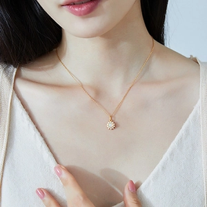 Détail d'un collier de fleurs dorées avec perles blanches porté par un mannequin