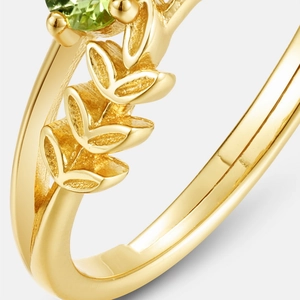 Macro d'une bague dorée S925 avec pierre précieuse verte et gravures de feuilles
