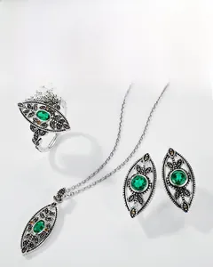 Macro view of vintage silver leaf jewelry set with oval emerald gemstones