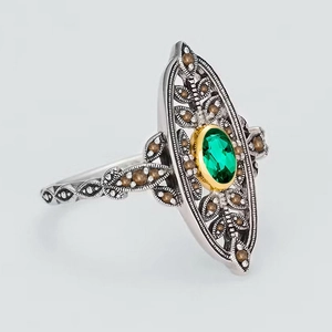Macro detail of vintage 925 silver leaf ring with oval emerald gemstone and carvings