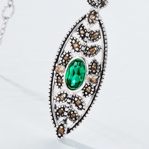 Macro detail of vintage emerald pendant in S925 silver with intricate filigree texture
