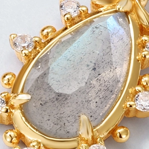Macro view of pear-shaped labradorite pendant with gold claw setting and halo stones