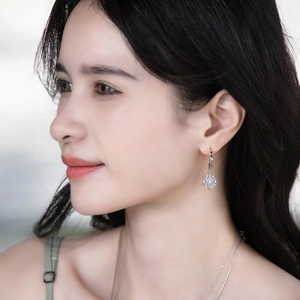 Close-up of model wearing silver snowflake earrings and necklace set with blue zircon