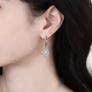 Elegant silver snowflake drop earrings with blue cubic zirconia on female model