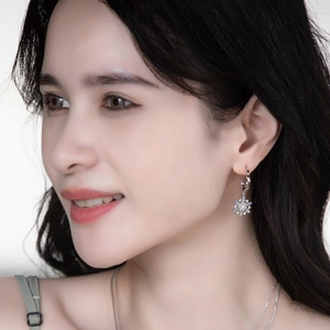 Detail of snowflake drop earrings featuring clear blue zircons on a silver hook
