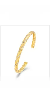 Detail of gold Mobius ring with braided texture and white zircon stones on white background