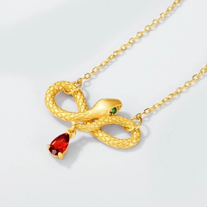 Detail of infinity snake pendant with red pear-cut gemstone and gold scales