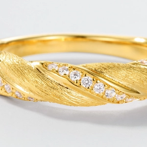 Golden Mobius ring with brushed texture and diagonal row of sparkling crystals