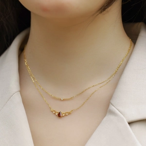 Double-layered gold necklace with pear-cut red garnet pendant and zircon accents on model