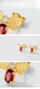 Macro detail of bee earring showing brushed gold finish and red garnet gemstone inlay