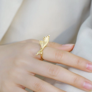 Bague vintage dorée avec nœud et zircons sur la main d'un mannequin avec tissu blanc