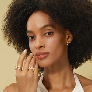 Detail of vintage style engraved maple leaf ring and pearl bird earrings on a model