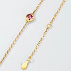 Gepolijste gouden vlinderketting met een robijnrode edelsteen aan een delicate fijne ketting