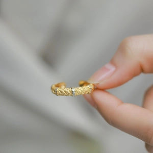 Vintage gold woven textured open ring with zircon stones on simple grey background