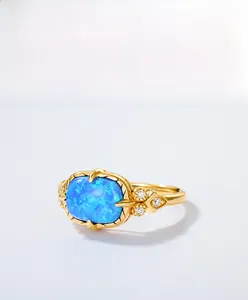 Macro shot of oval blue opal ring with vintage gold setting and white zircon accents