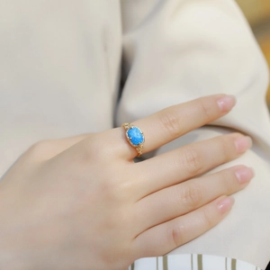 Vintage gold S925 silver ring with oval blue opal and diamond accents on a model's finger