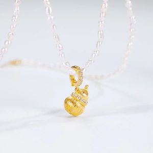 Pendentif gourde dorée au fini brossé sur un collier de perles d'eau douce blanches