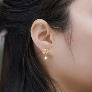 Handgefertigte gebürstete Goldblumen-Ohrringe mit weißer Perle am Modellohr