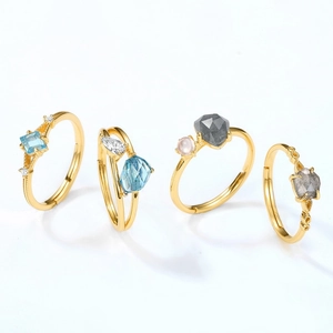 Set of four S925 silver gold-plated rings with various colorful gemstone cuts on white background