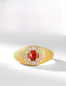 Dettaglio macro dell'anello con granato rosso e finitura in oro spazzolato e zirconi