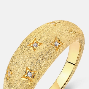 Macro shot of brushed gold ring featuring starburst engravings with small inset crystals