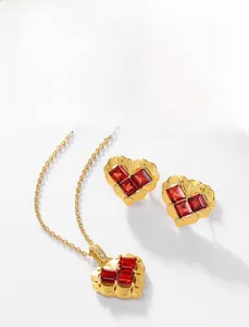 Detail of gold heart earrings and necklace set featuring red garnet gemstone inlays