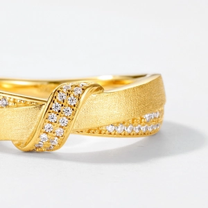 Macro view of gold double-layer brushed ring featuring pavé set crystals and metal texture