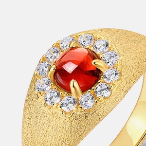 Vista macro di anello in oro 10K con cabochon di granato rosso e alone di zirconi