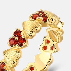 Macro view of gold heart ring bands featuring pleated texture and red garnet stones