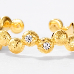 Macro detail of gold S925 silver ring with brushed texture and sparkling twin zirconia