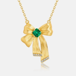 Elegant gold bow necklace with emerald cut green gemstone and micro-pavé accents