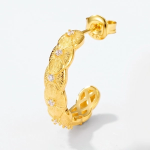 Detailed close-up of golden S925 silver C-shape earring with radial floral texture and zircon