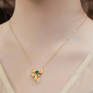 Elegant gold bow necklace featuring square emerald gemstone and sparkling diamond accents