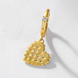 Detail of heart cookie-shaped earring with golden finish and sparkling zircon stones