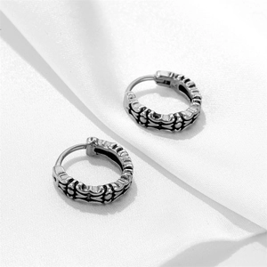 Detail of vintage silver gothic hoop earrings with intricate engraved patterns and hinge