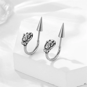 Detailed macro view of silver punk dragon head earrings with cone spike on stone pedestal