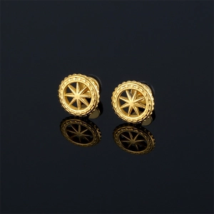 Macro shot of gold compass star stud earrings on a reflective black glass surface