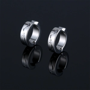 Silver stainless steel ear clips with crescent engravings on reflective black background