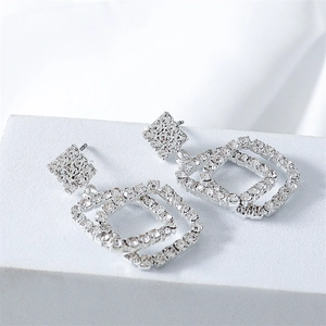 Macro detail of geometric silver earrings featuring shimmering double pavé squares