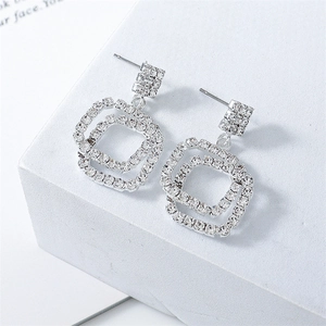 Macro shot of silver geometric square earrings with full zircon stones on white stand