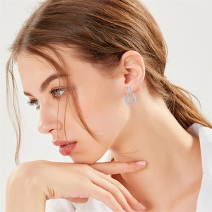 Detail view of a model wearing sparkling geometric square double hoop drop earrings