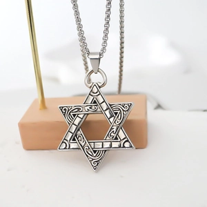 Macro view of vintage silver hexagram pendant with intricate scrollwork on pearl chain