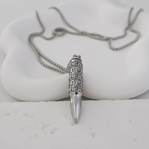 Vue détaillée du pendentif balle en argent vintage avec des caractères gravés